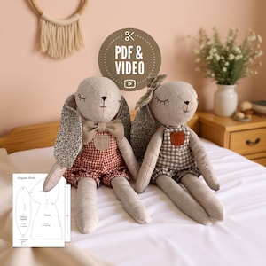 Puede incluir: Dos muñecos de conejito de peluche hechos a mano con orejas largas, que visten monos y pajaritas. Un conejito tiene un atuendo a cuadros rojos y blancos, el otro un atuendo a cuadros marrones y blancos. La imagen incluye un gráfico PDF y Video.