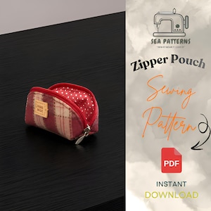 May include: A small, semi-circular zipper pouch featuring a red and beige plaid exterior with a small rectangular tag labeled HAND MADE. The interior is lined with red fabric featuring white polka dots. The pouch has a silver metal zipper.