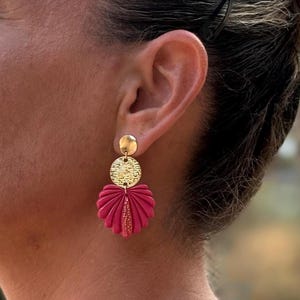 Peut inclure: Boucles d'oreilles dorées avec un dessus circulaire texturé et un bas rose vif en forme d'éventail. Les boucles d'oreilles sont de style pendant, avec un petit accent doré texturé au centre de l'éventail rose.
