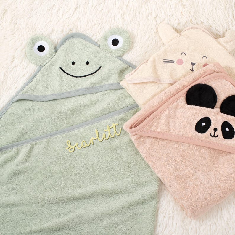 Puede incluir: Tres toallas con capucha para beb&eacute;s en colores pastel. Una es verde claro con caracter&iacute;sticas de rana y el nombre "Scarlett" bordado en amarillo. Las otras dos son un dise&ntilde;o de conejito y panda.