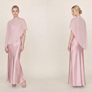 This elegant pastel pink silk gown with a detachable sheer cape offers a chic and refined silhouette, ideal for bridesmaids, wedding guests, or as a thoughtful bridal gift. Featuring a cowl neckline and asymmetrical cape hem, this dress creates a graceful look for any formal event. Whether for a wedding or bridal celebration, this dress is a beautiful and luxurious gift option for someone special.