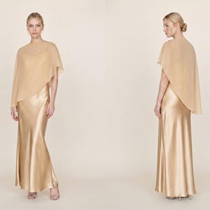 This light silver silk gown with a detachable sheer cape offers a stunning, elegant silhouette perfect for weddings or other formal events. With its soft cowl neckline and asymmetrical hemline, this dress flows gracefully with every movement. Ideal as a wedding gift or bridesmaid dress, it brings a refined and fashionable touch to any bridal celebration, making it a great gift for those looking to celebrate with a luxurious, timeless style.