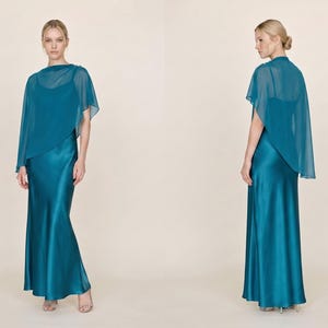 This teal silk gown with a detachable sheer cape brings modern elegance to any bridal celebration. The flattering cowl neckline and asymmetrical cape hem provide both comfort and style, making it the ideal choice for bridesmaids, wedding guests, or as a thoughtful bridal shower gift. The vibrant teal hue adds a bold yet refined touch, perfect for a memorable bridal party or elegant celebration.
