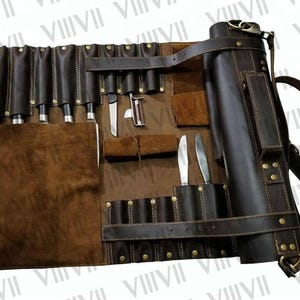 Peut inclure: Un rouleau de couteaux en cuir marron foncé avec plusieurs fentes et poches pour les outils culinaires. Le rouleau est ouvert, affichant divers couteaux et un éplucheur. Il comporte une bandoulière et une section de rangement cylindrique.