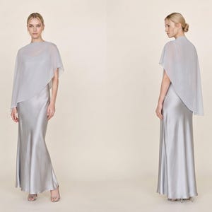 This stunning satin ivory silk dress with a detachable sheer cape is designed to make an impact at any bridal event. The cowl neckline and asymmetrical hemline create a graceful, flowing silhouette that flatters the figure beautifully. Ideal as a bridal party gift, this dress adds a touch of elegance to wedding celebrations and makes for a thoughtful gift for bridesmaids or wedding guests looking for a classic yet luxurious style.