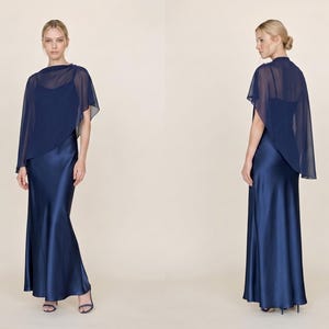 This beautiful navy silk maxi dress with a detachable sheer cape brings a touch of sophistication to any wedding or formal event. Featuring a cowl neckline and asymmetrical hem, it creates a striking and graceful silhouette. A perfect bridal party gift or wedding guest outfit, this dress combines classic elegance with contemporary design, making it an ideal choice for bridesmaids or for giving a loved one a thoughtful, stylish bridal gift.