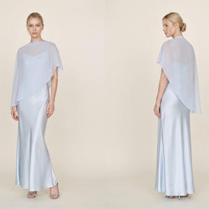 This beautiful pastel blue silk gown with a detachable sheer cape offers a graceful, elegant look perfect for wedding events or bridal celebrations. The cowl neckline and asymmetrical cape hem bring a refined and chic silhouette, making it an ideal choice for bridesmaids, wedding guests, or as a bridal shower gift. This dress radiates sophisticated style, making it an unforgettable addition to any bridal event or formal gathering.