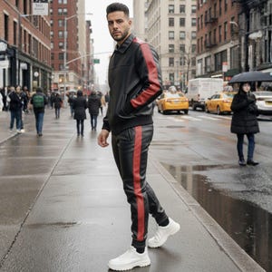 May include: A black leather jacket and matching pants with a red stripe down the side. The jacket has red stripes on the sleeves. The person is wearing white sneakers. The outfit is worn on a city street.