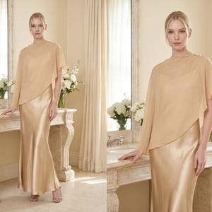 This soft champagne silk gown with a detachable sheer cape is perfect for creating a luxurious bridal look. Featuring a cowl neckline and asymmetrical cape hem, it’s the ideal choice for bridesmaids, wedding guests, or as an elegant bridal shower gift. The flowing silhouette ensures comfort and style, while the soft hue adds timeless elegance, making it a thoughtful and sophisticated gift for any bridal occasion.