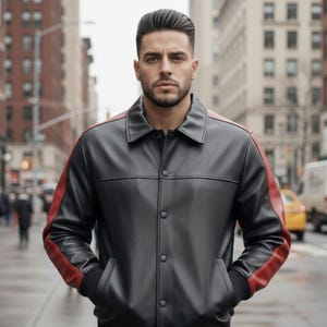 May include: A black leather jacket with red shoulder and sleeve accents. The jacket has a button-up front and a classic collar. The person is standing on a city street.