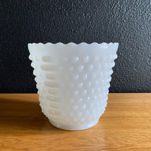 Könnte beinhalten: Weiße Milchglasvase mit einer strukturierten, unebenen Oberfläche. Die Vase hat einen gewellten Rand.