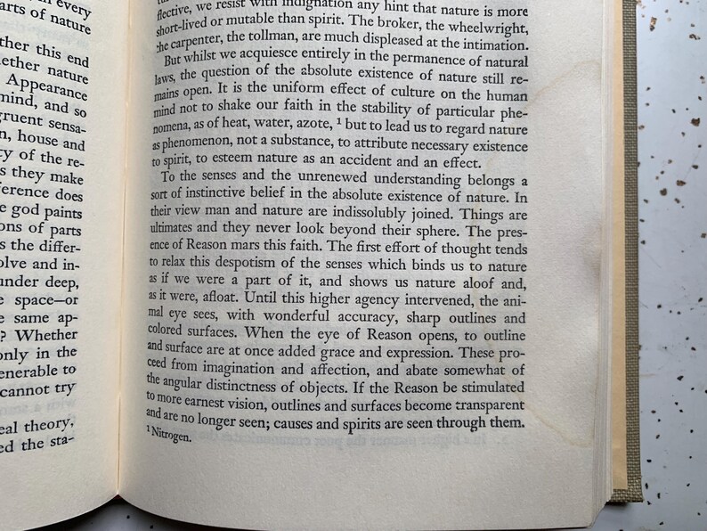 May include: Open book pages with printed text. The text is in black font on aged, off-white paper. The book's spine is visible on the right side, with a tan cover. The text discusses nature and reason.