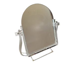 May include: A clear acrylic vanity mirror with an arched top. The mirror is supported by a clear acrylic frame and base. The mirror is designed to stand on a flat surface.