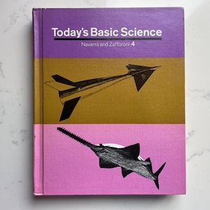 Może przedstawiać: Zabytkowy podręcznik zatytułowany "Today's Basic Science" z fioletową, złotą i różową okładką. Okładka zawiera ilustracje samolotu i piły. Książka jest oznaczona jako "Navarra and Zaffaroni 4".