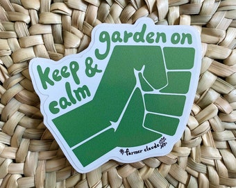 May include: Green sticker with the text "Keep & calm garden on" and a green hand-shaped graphic. The sticker has a white border and the text "#farmer claude" at the bottom.