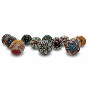 May include: Eleven ceramic cabinet knobs with floral patterns in various colours. The knobs are round and feature hand-painted designs in red, blue, yellow, and green. Each knob has a unique floral design, suitable for drawers or cabinets.
