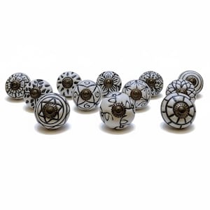 Può includere: Una collezione di pomelli per mobili in ceramica bianca con motivi decorativi neri. Ogni pomello presenta un design unico, tra cui motivi floreali, geometrici e astratti. I pomelli hanno ferramenta in metallo color bronzo. Questi pomelli decorativi sono ideali per aggiungere un tocco di eleganza ai mobili.