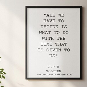 May include: A framed print with a black border, displaying a quote by J.R.R. Tolkien: "ALL WE HAVE TO DECIDE IS WHAT TO DO WITH THE TIME THAT IS GIVEN TO US." The author's name and book title are below the quote.