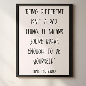 May include: Black framed print with the quote "BEING DIFFERENT ISN'T A BAD THING. IT MEANS YOU'RE BRAVE ENOUGH TO BE YOURSELF" by Luna Lovegood. The text is in a handwritten style font on a cream background.