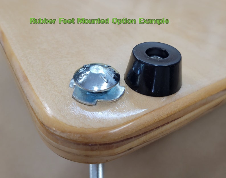 May include: Close-up of two rubber feet, one mounted on a piece of wood. The rubber feet are black and have a small hole in the center. The text "Rubber Feet Mounted Option Example" is visible in the top left corner of the image.