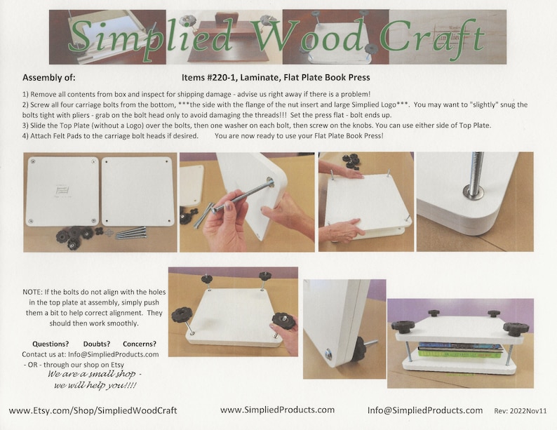 May include: A white flat plate book press with four black knobs and a book on top. The press is made of laminate and is used for pressing books flat.