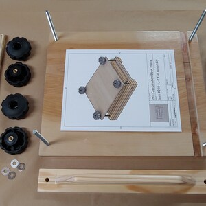 May include: A wooden book press kit featuring a flat base board with four vertical metal rods, a separate wooden handle piece, four black plastic knobs, four metal washers, and an assembly instruction sheet labeled 210 Combination Book Press.