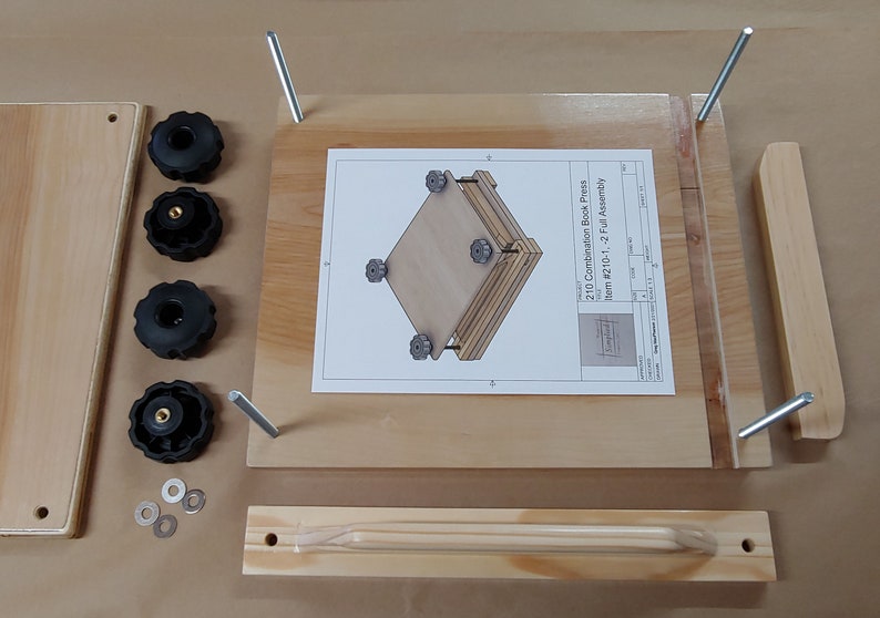May include: A wooden book press kit featuring a flat base board with four vertical metal rods, a separate wooden handle piece, four black plastic knobs, four metal washers, and an assembly instruction sheet labeled 210 Combination Book Press.
