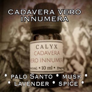 May include: A small, dark glass bottle with a black cap. The label reads "CALYX CADAVERA VERO INNUMERA" and lists Palo Santo, Musk, Lavender, and Spice. The bottle contains 10 ml of fragrance.