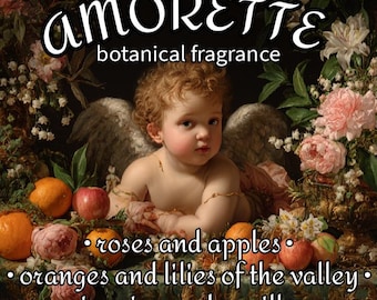 May include: An image featuring the word "AMORETTE" above "botanical fragrance". The image includes a cherub with wings, surrounded by flowers, oranges, and apples. The text lists "roses and apples", "oranges and lilies of the valley", and "jasmine and vanilla".