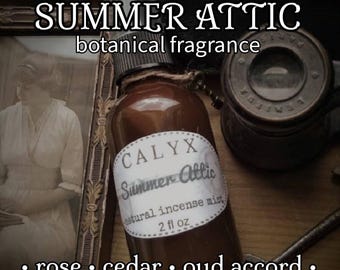 May include: A brown glass spray bottle labeled "CALYX Summer Attic natural incense mist 2 fl oz" with the text "SUMMER ATTIC botanical fragrance." The scent includes rose, cedar, and oud accord. The bottle is tied with twine.