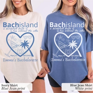 Puede incluir: Dos camisetas de manga corta y cuello redondo, una de color marfil con estampado azul y otra azul con estampado blanco. Ambas incluyen el texto Bachisland a bombshell bride has entered the villa, un corazón con una copa de martini, palmera, anillos, Miami, FL est. 2026 y Emma's Bachelorette.