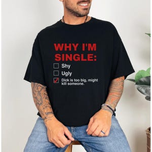 May include: A black short-sleeved t-shirt featuring red text that reads WHY I'M SINGLE: followed by a checklist with white text. The list includes Shy, Ugly, and a third option with a red checkmark: Dick is too big, might kill someone.