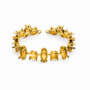 Può includere: Una base per bracciale color oro caratterizzata da una serie di castoni a griffe vuoti e collegati, progettati per ospitare pietre preziose. La struttura circolare è composta da molteplici maglie metalliche con piccole griffe.