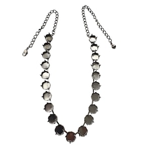 May include: A silver-toned necklace with a series of round, iridescent stones. The stones are connected by a delicate chain, and the necklace has an adjustable length. The necklace is displayed against a white background.