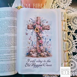 May include: A vellum bible tip-in page featuring a wooden cross adorned with colorful flowers, butterflies, and stones. The text reads, "I will cling to the Old Rugged Cross." The translucent page is inserted into an open book with indexed tabs.