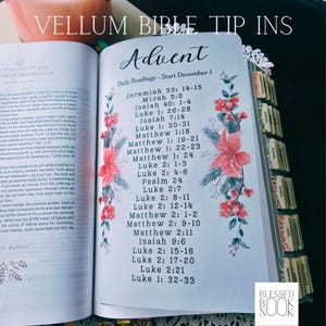 May include: A vellum bible tip-in page featuring the text Advent and Daily Readings - Start December 1, followed by a list of scripture references. The page is decorated with watercolor-style red poinsettia flowers and green pine branches.