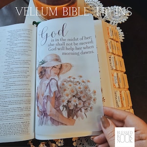 May include: A vellum bible tip-in page featuring an illustration of a person in a sun hat holding a bouquet of daisies. The text reads: God is in the midst of her; she shall not be moved; God will help her when morning dawns. The page is translucent.