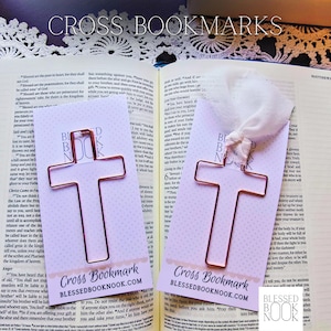 May include: Two copper-colored wire cross bookmarks on light purple backing cards. Each card features the text Cross Bookmark and BLESSEDBOOKNOOK.COM. One bookmark includes a white fabric ribbon tied to the top of the wire cross shape.