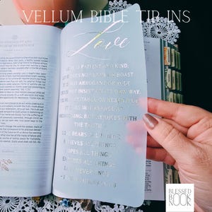 May include: A translucent vellum bible tip-in sheet featuring gold foil calligraphy of 1 Corinthians 13:4-8. The text reads Love is patient and kind, love does not envy or boast, it is not arrogant or rude, it does not insist on its own way.