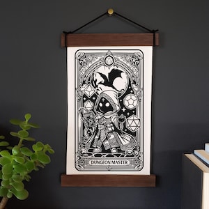 May include: Black and white Dungeon Master art print, displayed with a wooden frame and hanging cord. The illustration features a robed figure holding a book, surrounded by dice and a dragon. The text "Dungeon Master" is at the bottom.