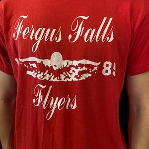 Puede incluir: Una taza de cer&aacute;mica blanca con un asa negra y el texto "But First, Coffee" en negro, con una fuente de estilo manuscrito. La taza est&aacute; sobre una superficie blanca.