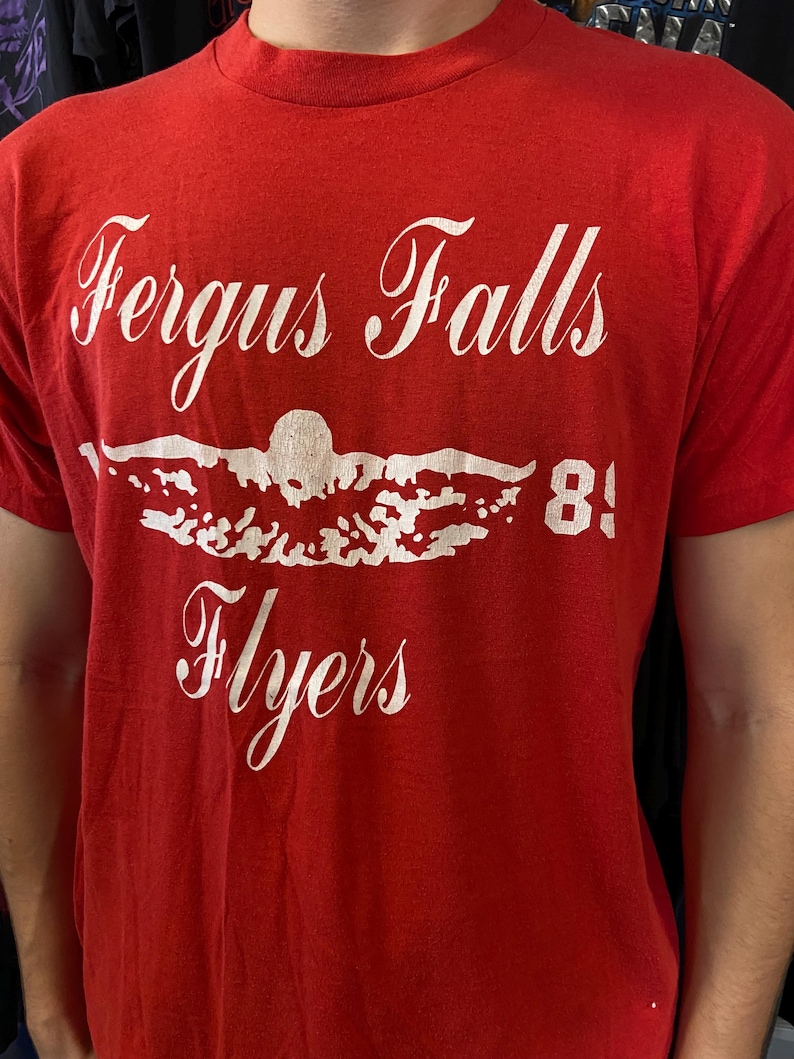 Puede incluir: Una taza de cer&aacute;mica blanca con un asa negra y el texto "But First, Coffee" en negro, con una fuente de estilo manuscrito. La taza est&aacute; sobre una superficie blanca.