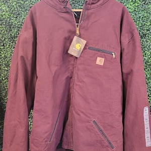 Peut inclure: Une veste à capuche bordeaux avec une fermeture éclair intégrale, une capuche à cordon de serrage et des manches longues. Elle présente une poche poitrine zippée, deux poches avant inférieures et un écusson de marque Carhartt carré.