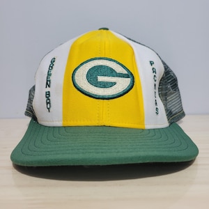 Op de afbeelding: Groene en gele baseballcap met het Green Bay Packers logo. De cap heeft een groene klep, een geel middenpaneel met het logo van het team en witte en groene accenten. De teksten "GREEN BAY" en "PACKERS" zijn op de zijkanten geborduurd.