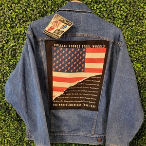 以下が含まれることがあります： ローリング・ストーンズのロゴとアメリカ国旗のデザインが施された大きなパッチが付いた、青色のデニムジャケット。「ROLLING STONES STEEL WHEELS THE NORTH AMERICAN TOUR 1989」と書かれたパッチ。ローリング・ストーンズのロゴが入った小さなタグが付いています。