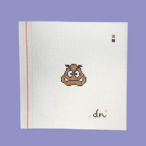 May include: A white canvas with a cross-stitched brown Goomba character from the Super Mario Bros. video game series. The canvas has a red and orange stitched border on the left side and the initials "dn" in black with yellow accents.