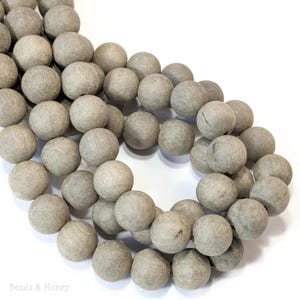 May include: A strand of light gray wooden beads. The beads are round and smooth, and they are strung together on a clear string.
