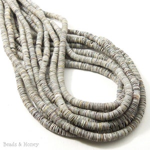 May include: Strands of small, flat, round beads in shades of gray, white, and tan. The beads are strung together, creating a coiled and layered effect. The image is well-lit, showcasing the texture and color variations of the beads. The beads are likely for jewelry making.