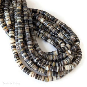 May include: Strands of flat, round beads in shades of black, gray, and cream. The beads are strung together, forming a coiled pattern. The beads have a natural, organic appearance, suitable for jewelry making or craft projects.