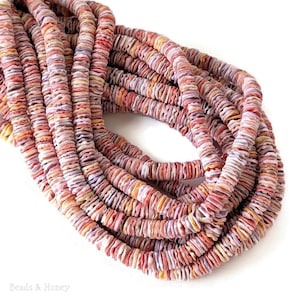 May include: Strands of colorful, flat shell beads in shades of red, pink, orange, and purple. The beads are stacked in rows, creating a textured, organic look. The image is well-lit, highlighting the natural variations in color and shape.
